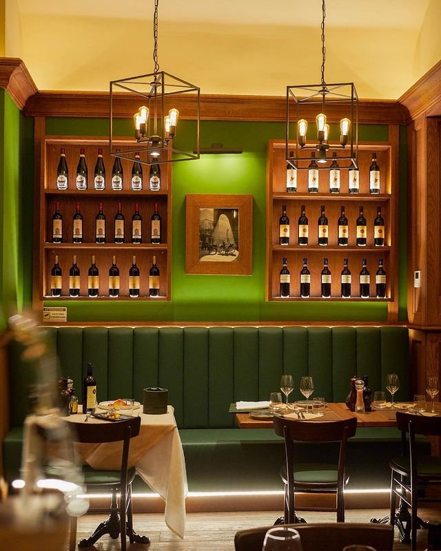 Interno accogliente dell'Osteria del Corso a Firenze. Tavoli apparecchiati con cura, bottiglie di vino esposte e un'atmosfera intima e rilassante. Ristorante Firenze